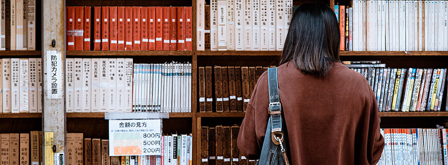 Woman reading a book in front of a wall of books in a library. Instagram marketing for dispensaries. Dispensary marketing plan. How to promote a dispensary on Instagram.